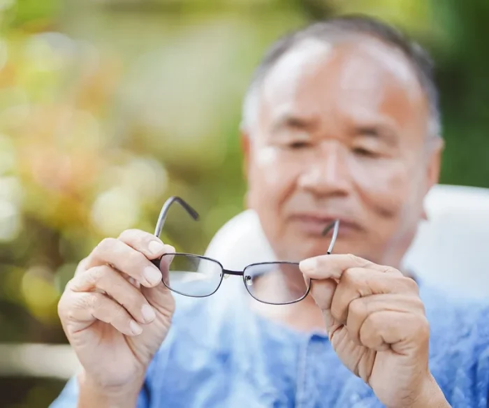 senior man with blurry vision taking off glasses