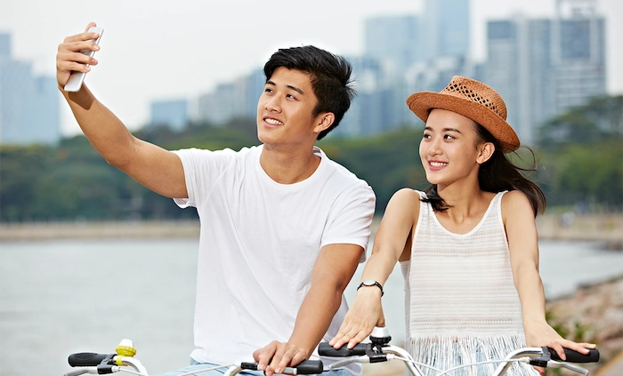 young asian couple riding bikes with cityscape in the background