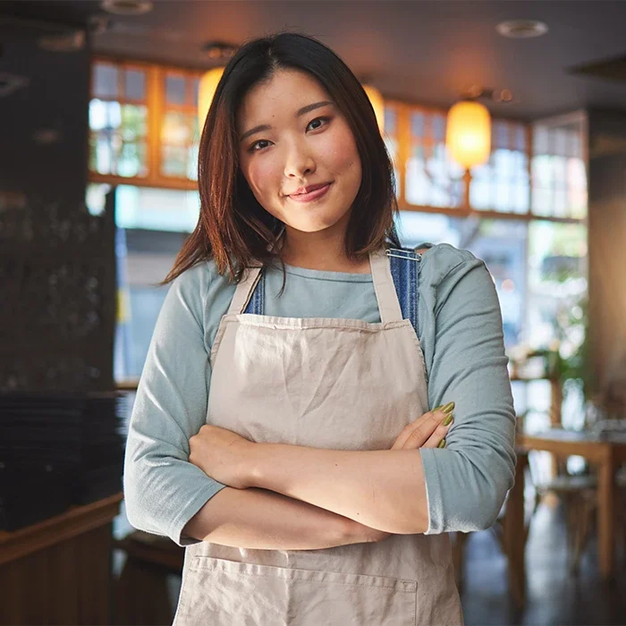 young female restaurant owner in apron with crossed arms